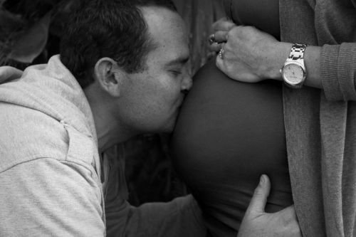 tėvas bučiuoja nėščią pilvą