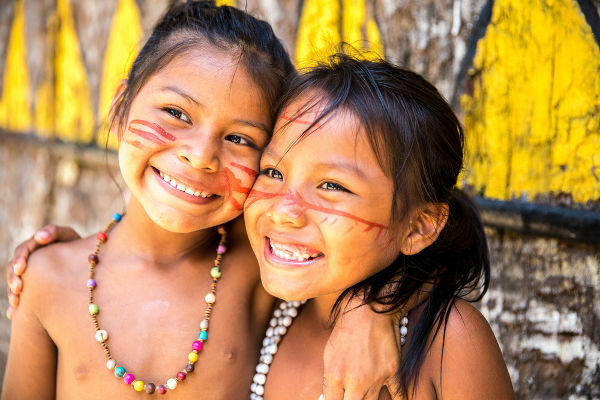 Copii indigeni cu picturi tradiționale pe față și coliere tipice.