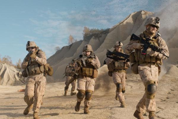 Skvadron av amerikanska soldater utrustade, beväpnade och springande under en militär operation i öknen.