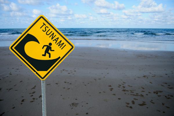 Sebuah tanda memperingatkan risiko tsunami, sebuah fenomena yang terutama disebabkan oleh gempa bumi yang kuat.