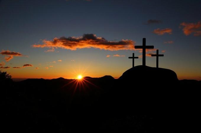 tre kors på toppen av et fjell ved solnedgang