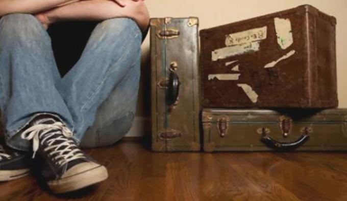Fiatal férfi ül a régi bőröndök mellett