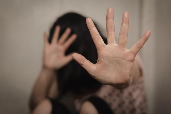 Suddig bild av en kvinna med händerna upphöjda som ett tecken på skydd i ett sammanhang av våld mot kvinnor.