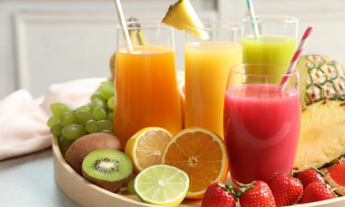 Klaasid puuviljamahladega, mille ümber on puuviljad kandikul, laual