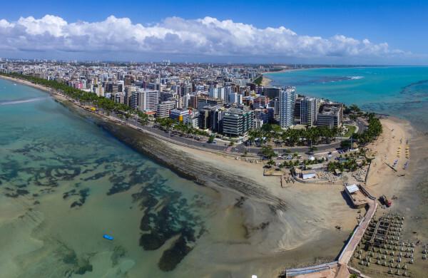 Photo of part of Maceió seen from above and made up of buildings surrounded by the sea.