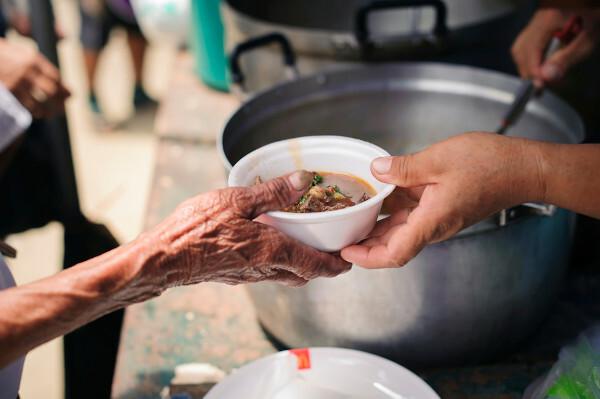 Soup pan being passed from hand to hand as a gesture of charity.