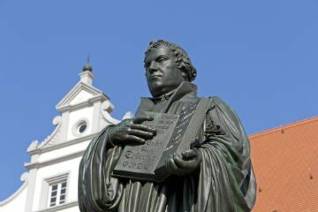 Statue of Martin Luther in Wittemnber, Germany, holding a Bible in his hands.