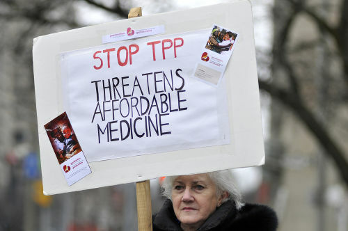 Protestētājs ar plakātu pret TPP apstiprinājumu, kurā teikts: "Apturiet TPP, draudi par pieņemamām zālēm" *