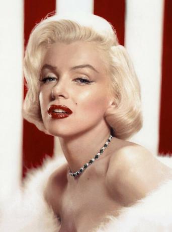Marilyn Monroe with red lipstick and necklace wearing white strapless dress.