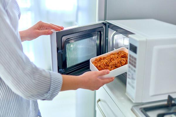 Persona che inserisce il cibo nel forno a microonde.