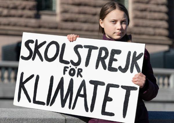 Greta Thunberg demonstrating in Stockholm holding a sign that reads “School strike for the climate”.
