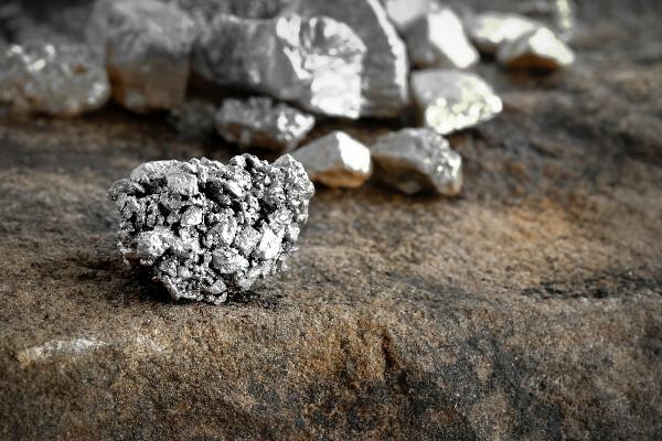 पत्थर के फर्श पर चांदी के टुकड़े, धात्विक खनिज संसाधन का एक उदाहरण।