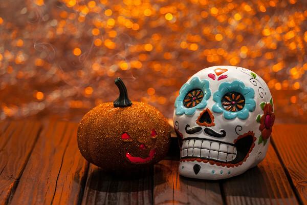  Halloween pumpkin next to Day of the Dead skull.