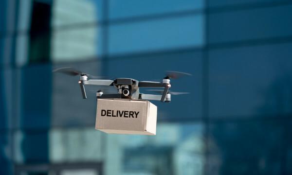 Drone, üzerinde “Teslimat” yazan bir kutu taşıyor.