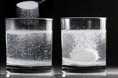 Reaction between effervescent antacid and water in two different situations: in the first glass, the antacid is powdered; in the second, it's in tablet