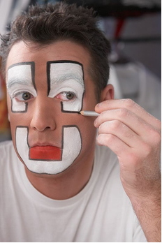 Clown applying whitewash (zinc oxide) as makeup.
