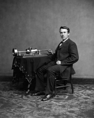 Thomas Edison sitting next to a phonograph