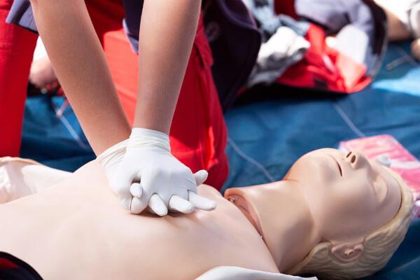 Osoba trénující srdeční resuscitaci na figuríně, opatření, které může pomoci v případech náhlého onemocnění.